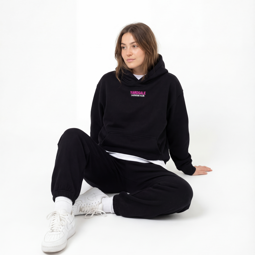 Person wearing a black hoodie with a logo sitting on a white background