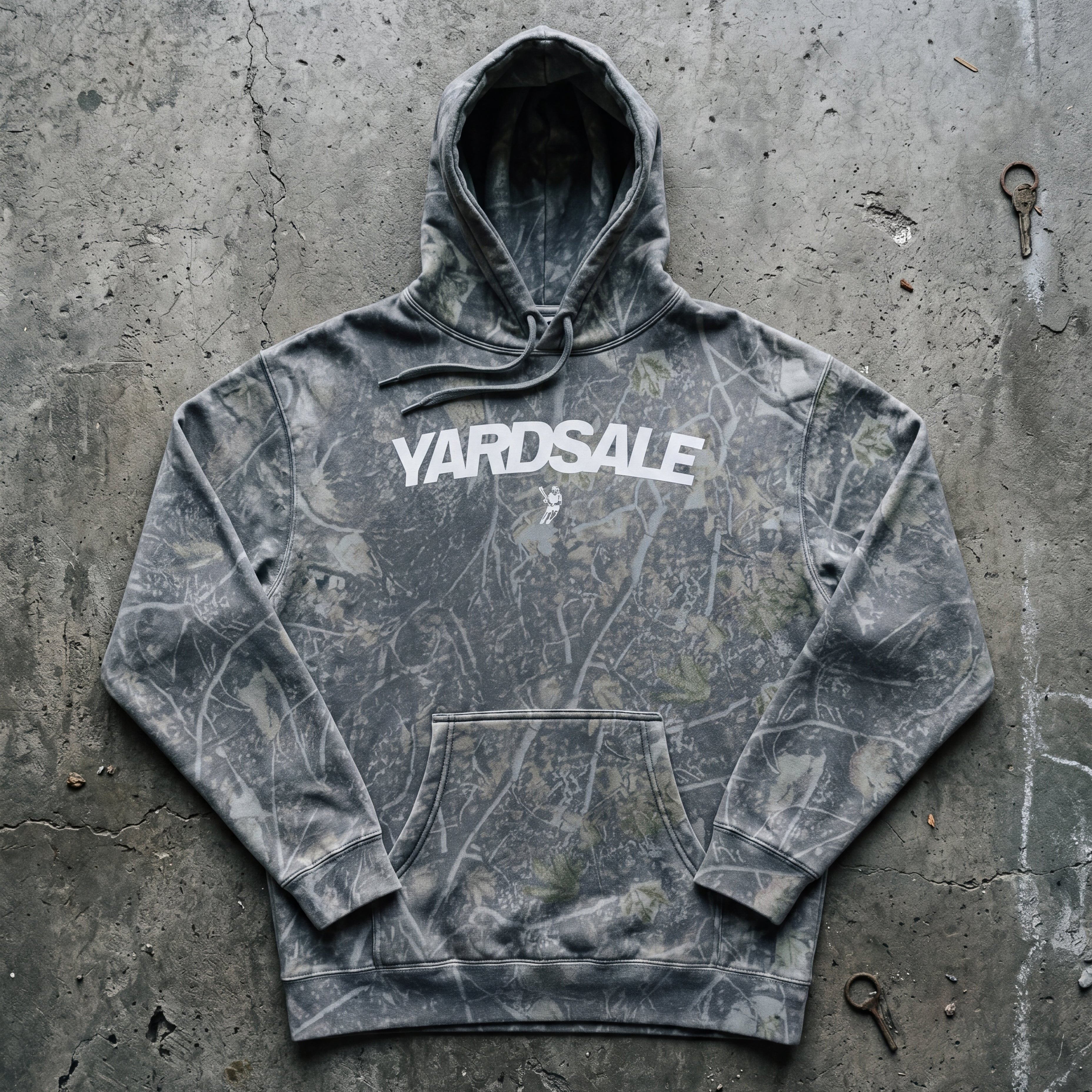 Gray tie-dye hoodie with 'Yardsale' text on a concrete surface