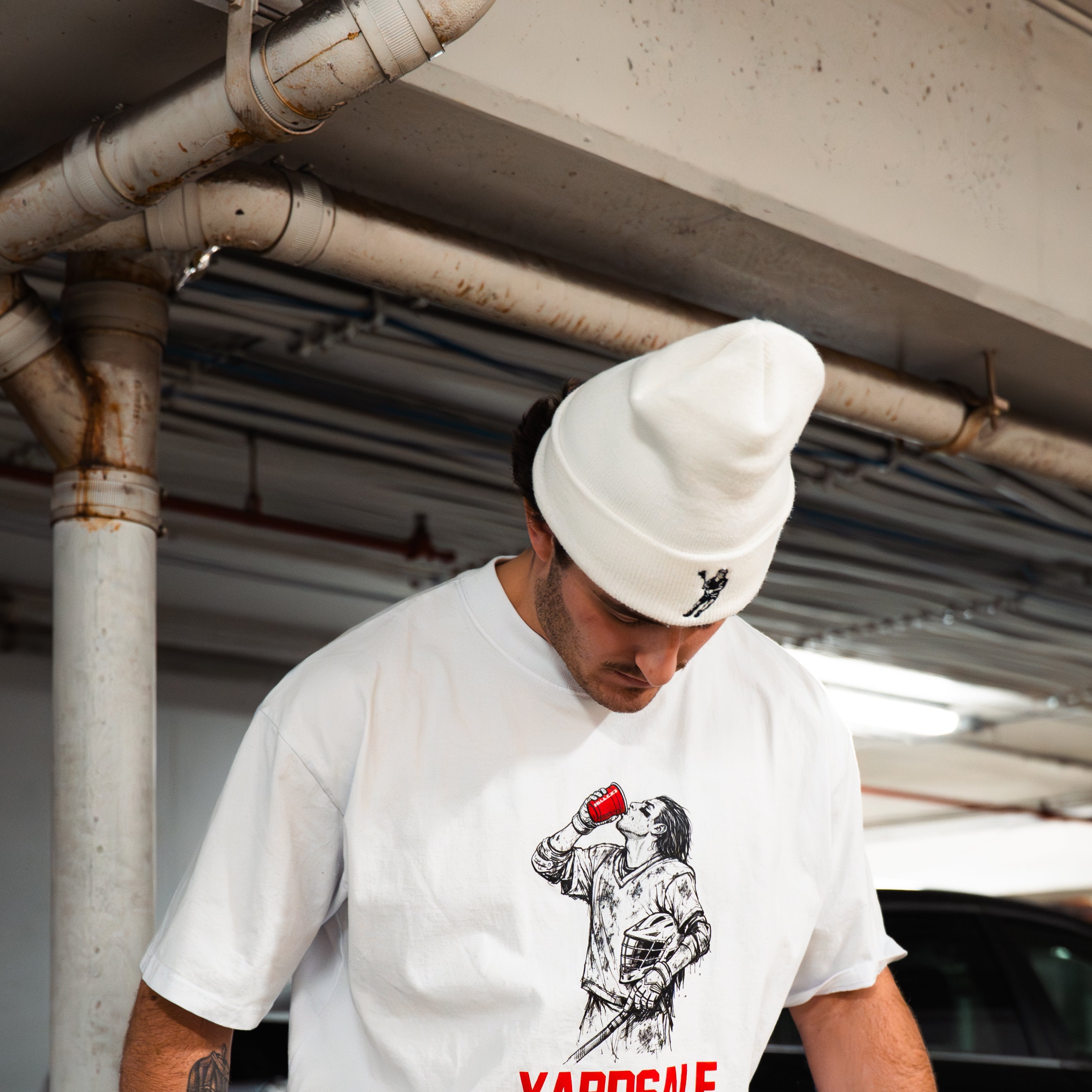 Person wearing a white t-shirt with 'Yardsale' logo in an urban setting