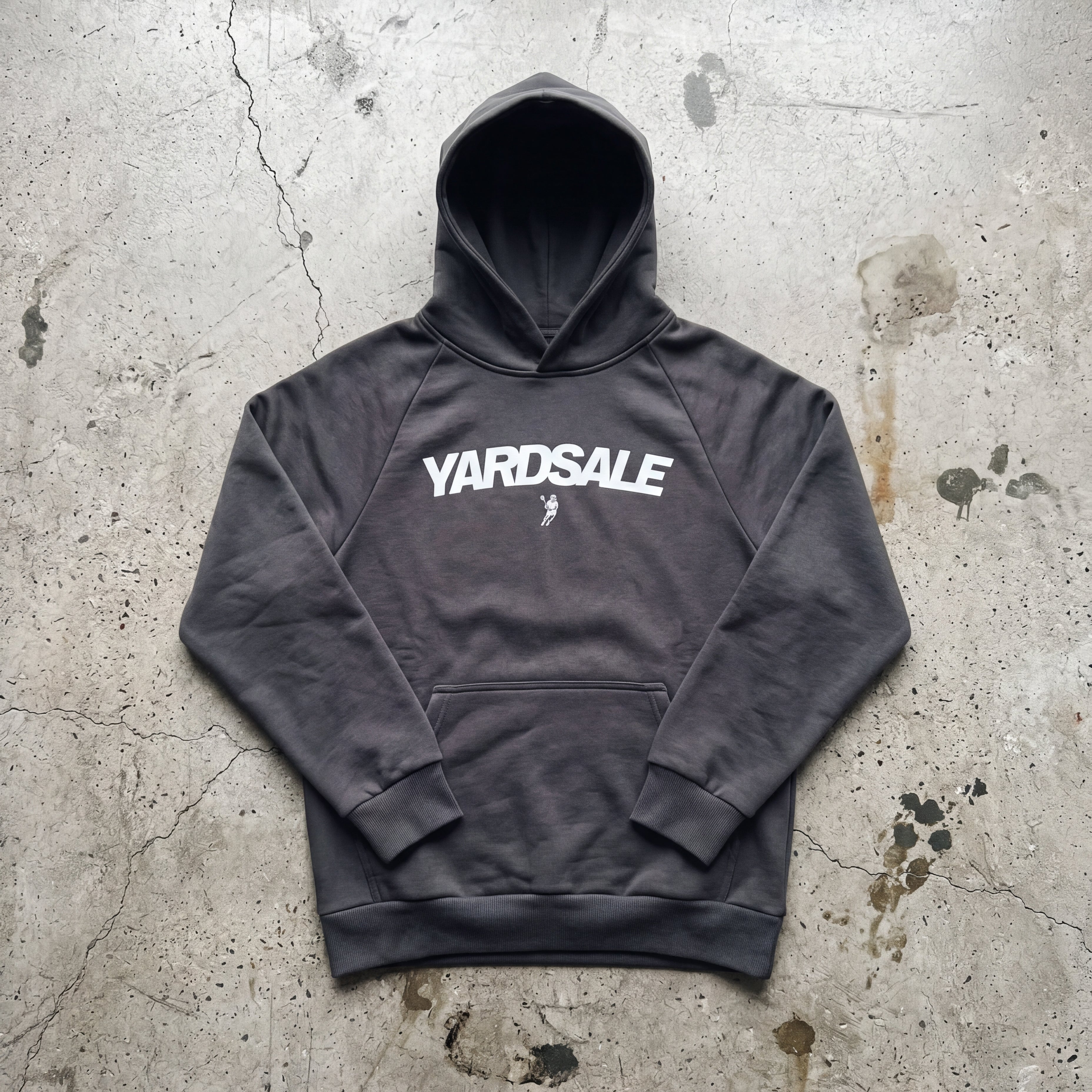 Gray hoodie with 'Yardsale' logo on a textured concrete surface