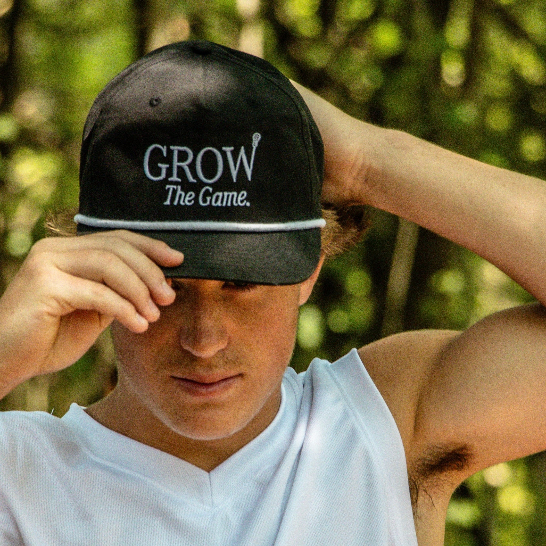Person wearing a black cap with 'GROW The Game' text in a forest setting