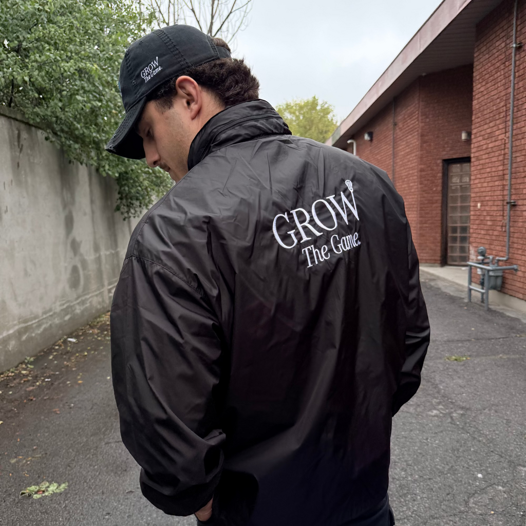 Person wearing a black jacket with 'GROW The Game' text, standing outdoors.