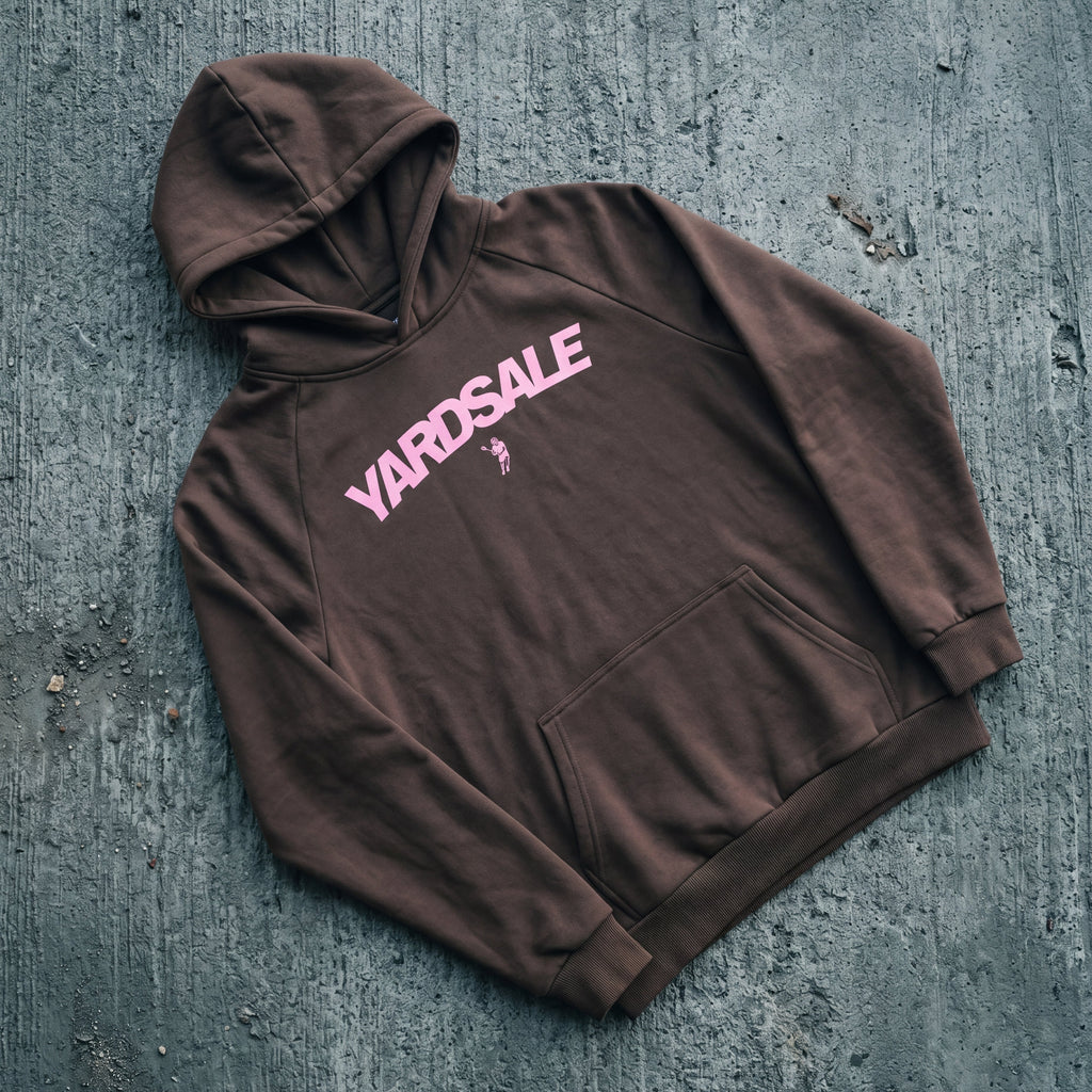 Brown hoodie with 'Yardsale' text on a textured gray surface