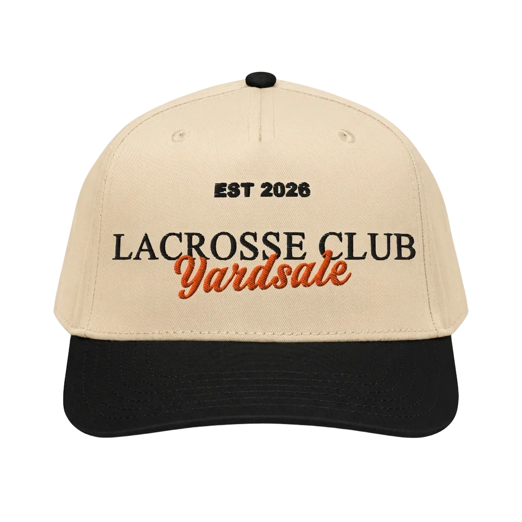A beige and black baseball cap with embroidered text reading 'EST 2026 LACROSSE CLUB Yardsale' on a light gray background.