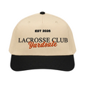 A beige and black baseball cap with embroidered text reading 'EST 2026 LACROSSE CLUB Yardsale' on a light gray background.